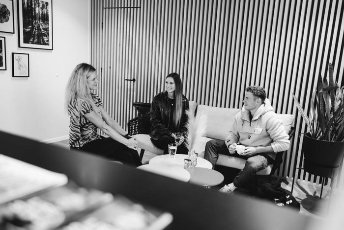 Drei Personen sitzen entspannt in einer modernen Lounge und unterhalten sich gut gelaunt.