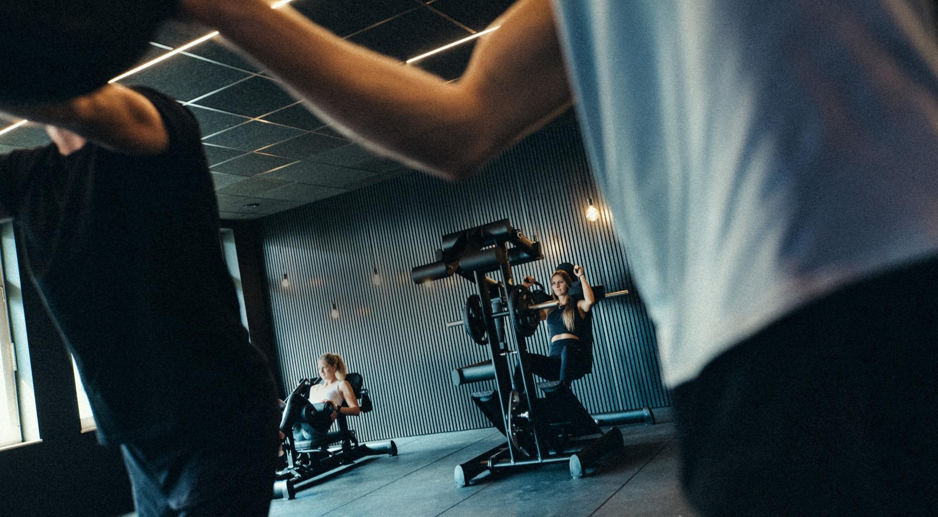 Mehrere Personen trainieren an verschiedenen Geräten in einem Fitnessstudio.