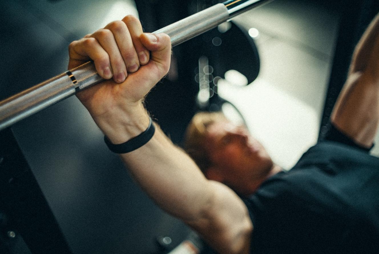 Nahaufnahme einer Hand, die eine Langhantel beim Training greift.