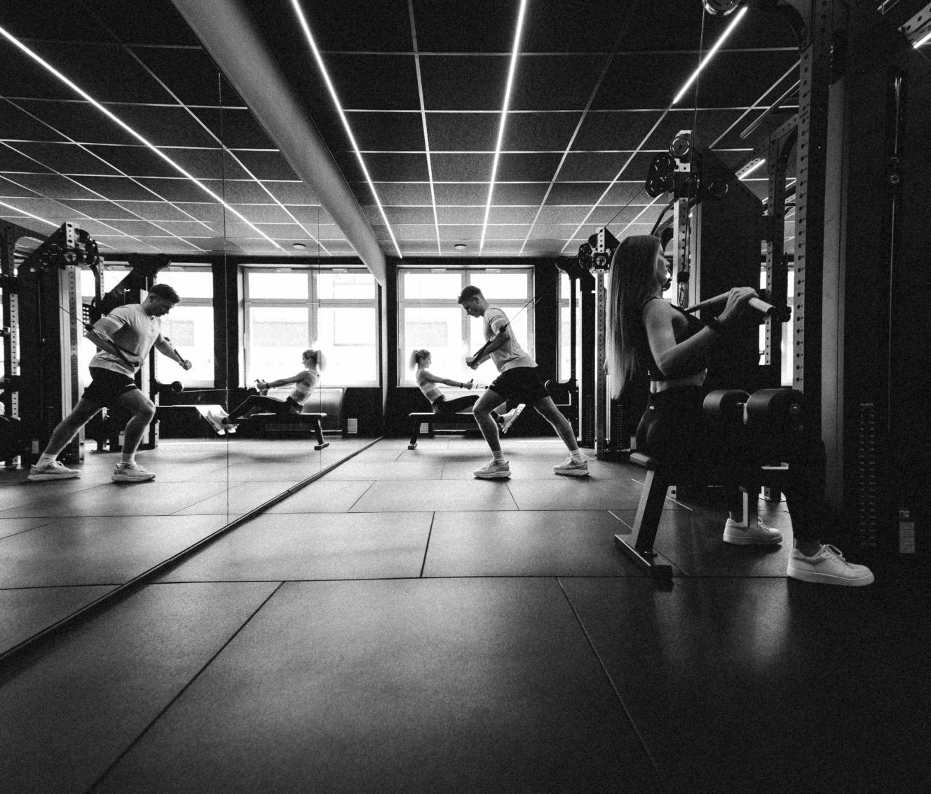 Mehrere Personen trainieren gleichzeitig an verschiedenen Geräten in einem Fitnessstudio.