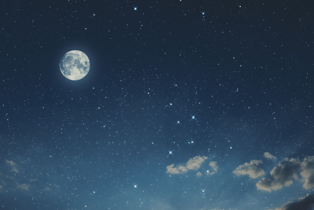 Heller Vollmond am sternklaren Nachthimmel mit einigen Wolken am unteren Rand.