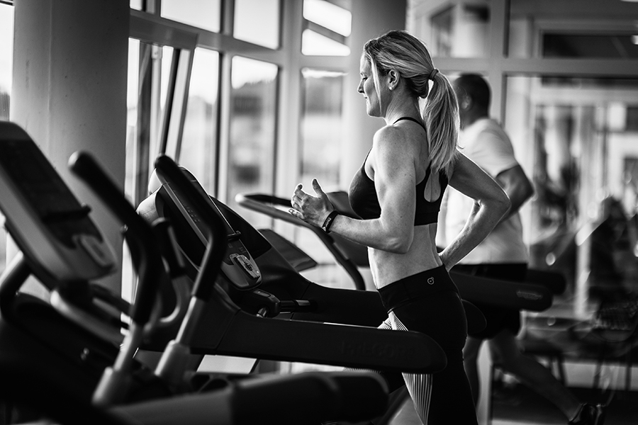Frau joggt auf dem Laufband in einem Fitnessstudio.